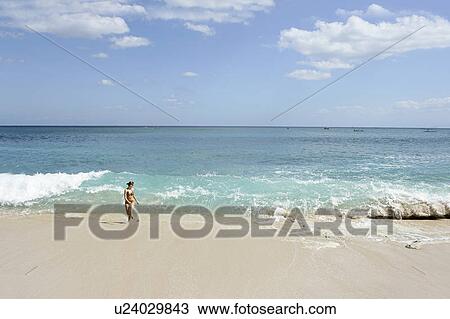Stock Image - View of a woman walking on a beach.. Fotosearch