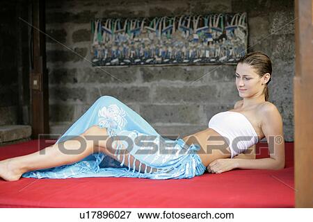 Stock Photo - A young woman sitting on red cushion.. Fotosearch