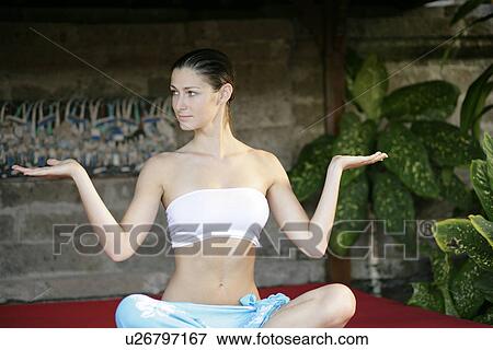 Stock Photo - A young woman sitting on red cushion.. Fotosearch