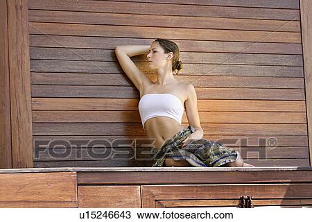View of a woman sitting against wooden wall. View Large Photo Image Stock Image - View of a woman sitting against wooden wall.. Fotosearch