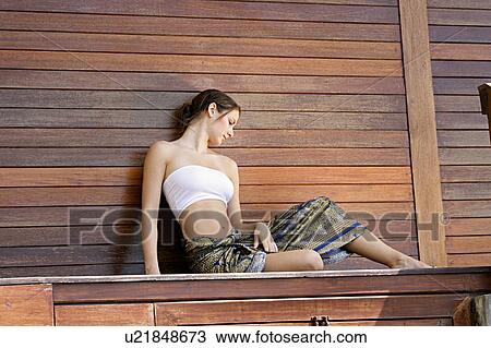 View of a woman sitting against wooden wall. View Large Photo Image Stock Image - View of a woman sitting against wooden wall.. Fotosearch