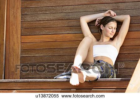 View of a woman sitting against wooden wall. View Large Photo Image Stock Photography - View of a woman sitting against wooden wall.. Fotosearch