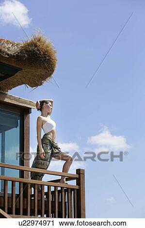 View of a woman standing in wooden balcony. View Large Photo Image Stock Image - View of a woman standing in wooden balcony.. Fotosearch