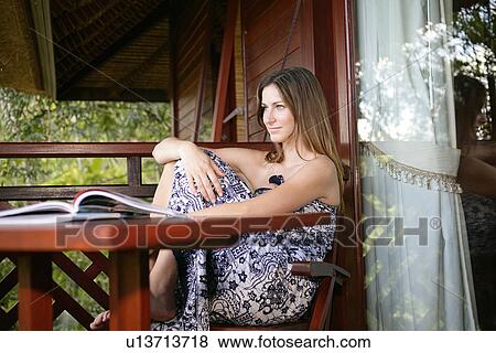 Stock Photo - View of a young woman sitting on chair.. Fotosearch