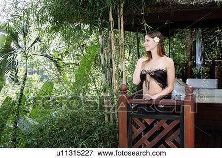 Stock Photo - View of a young woman standing in balcony.. Fotosearch
