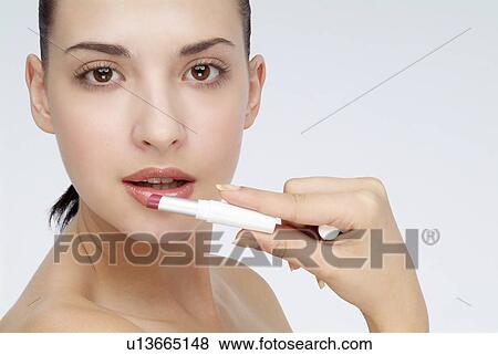 Close-up of a young woman applying lip stick. View Large Photo Image Stock Photo - Close-up of a young woman applying lip stick.. Fotosearch