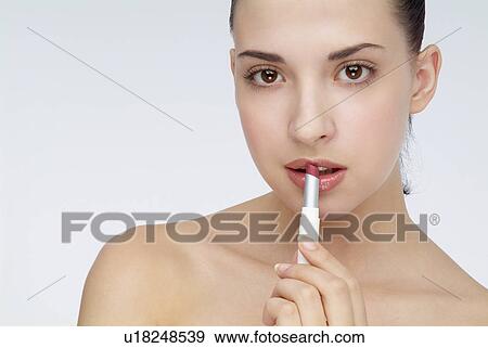 Close-up of a young woman applying lip stick. View Large Photo Image Stock Photo - Close-up of a young woman applying lip stick.. Fotosearch