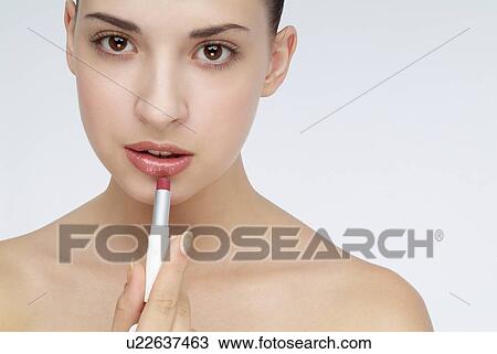 Stock Image - Close-up of a young woman applying lipstick.. Fotosearch