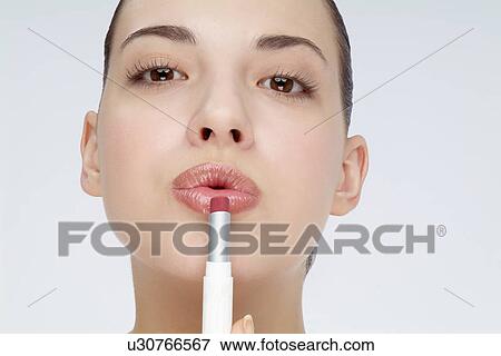 Close-up of a young woman applying lipstick. View Large Photo Image Stock Photo - Close-up of a young woman applying lipstick.. Fotosearch