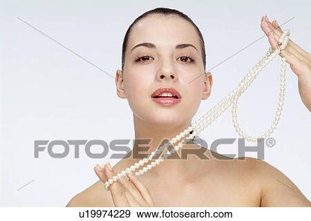 Stock Photo - Close-up of a young woman holding pearl necklace.. Fotosearch