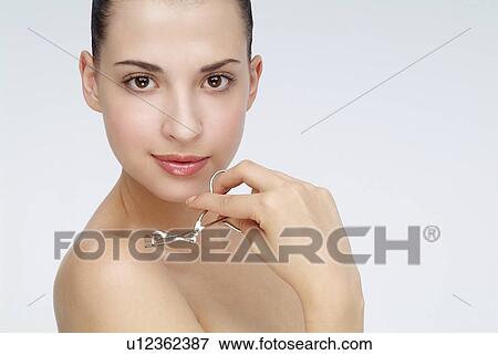 Close-up of a young woman holding eyelash curler. View Large Photo Image Stock Photo - Close-up of a young woman holding eyelash curler.. Fotosearch