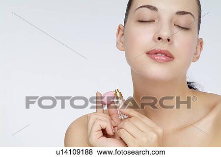 Close-up of a young woman holding perfume bottle. View Large Photo Image Stock Photo - Close-up of a young woman holding perfume bottle.. Fotosearch
