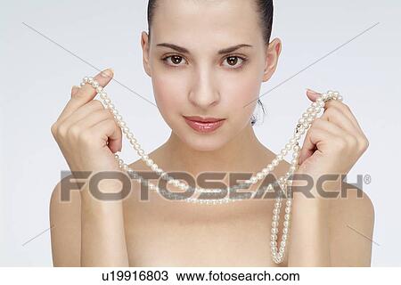 Stock Image - View of a woman holding necklace.. Fotosearch