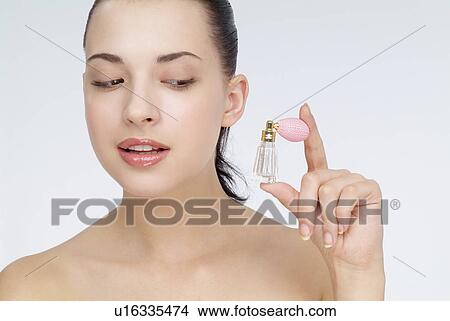 View of a young woman holding perfume bottle. View Large Photo Image Picture - View of a young woman holding perfume bottle.. Fotosearch