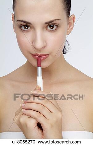 Stock Image - Close-up of a young woman applying lipstick.. Fotosearch