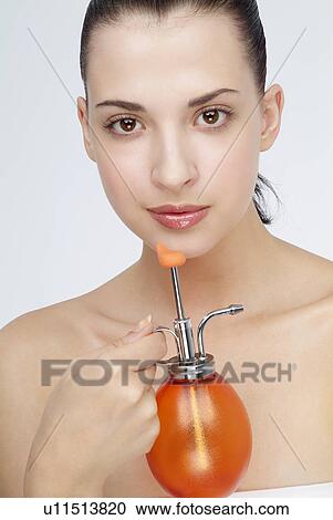Stock Image - Close-up of a young woman holding perfume bottle.. Fotosearch