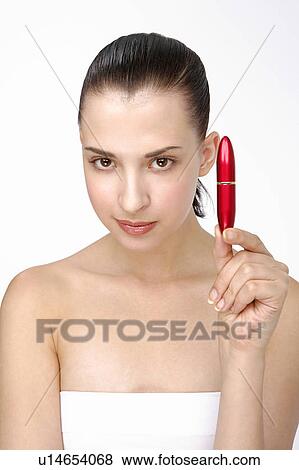 Stock Photo - Close-up of a young woman holding lipstick.. Fotosearch