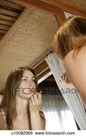 Stock Photograph - A woman applying lipstick.. Fotosearch