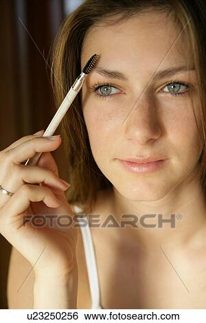 Stock Photograph - A woman combing eyebrow.. Fotosearch