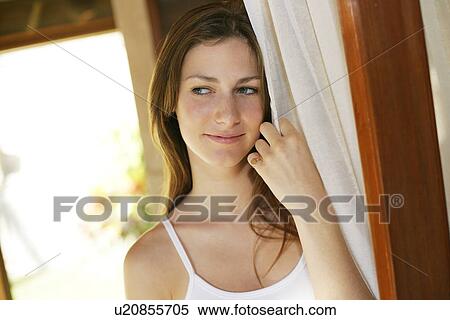Stock Photography - A woman holding curtain.. Fotosearch