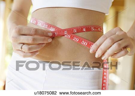 A woman measuring her waist. View Large Photo Image Stock Image - A woman measuring her waist.. Fotosearch