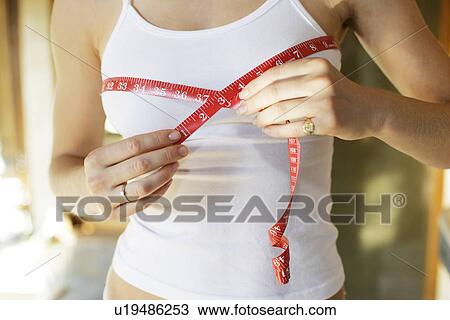 Stock Image - Midsection of a woman measuring her body.. Fotosearch