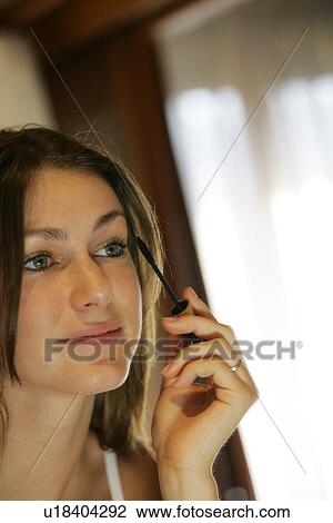 Stock Image - View of a young woman applying mascara.. Fotosearch