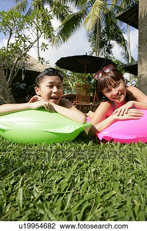 Stock Image - Portrait of two teenage girls lying on floats.. Fotosearch