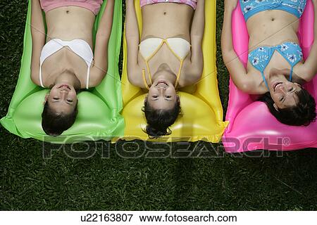Three teenage girls lying on inflatable in swimsuits. View Large Photo Image Stock Photo - Three teenage girls lying on inflatable in swimsuits.. Fotosearch