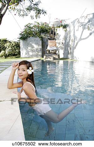 Stock Image - View of a teenage girl leaning by a swimming pool.. Fotosearch