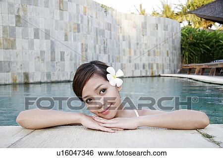 Stock Photograph - View of a teenage girl leaning by a swimming pool.. Fotosearch