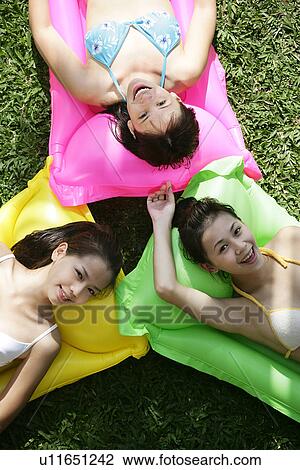 View of three teenage girls lying on floats. View Large Photo Image Stock Image - View of three teenage girls lying on floats.. Fotosearch
