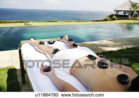 Stock Image - View of a female undergoing a hot stone therapy.. Fotosearch
