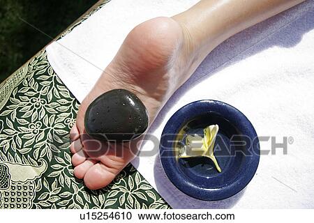 Stock Image - View of a heavy pebble on a person’s foot. Fotosearch
