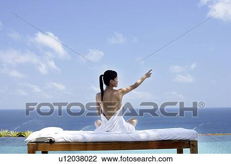 Stock Image - View of a seminude teenage girl on a bed against the sea.. Fotosearch