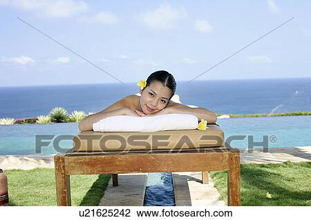 Stock Image - View of a teenage girl relaxing on a bed.. Fotosearch