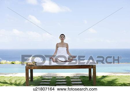 View of a teenage girl sitting on a bed. View Large Photo Image Picture - View of a teenage girl sitting on a bed.. Fotosearch