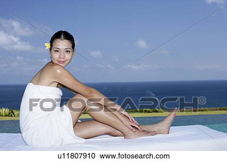 Stock Image - View of a teenage girl sitting on a bed. Fotosearch