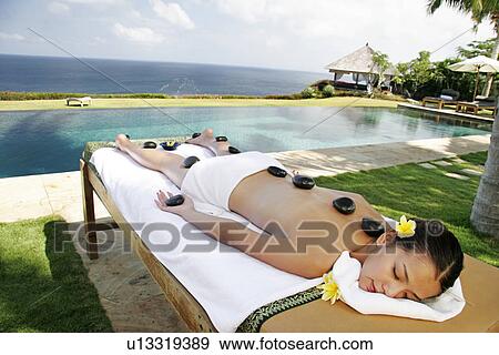 Stock Photo - View of a teenage girl undergoing a hot stone therapy.. Fotosearch