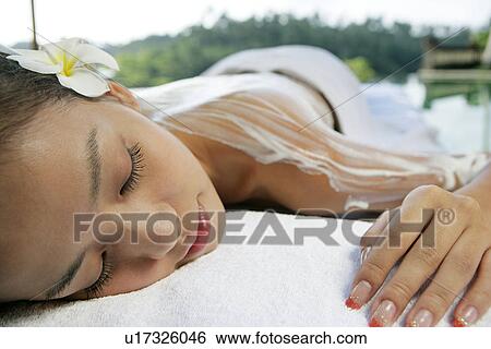 Stock Photograph - View of a teenage girl with cream on her back.. Fotosearch