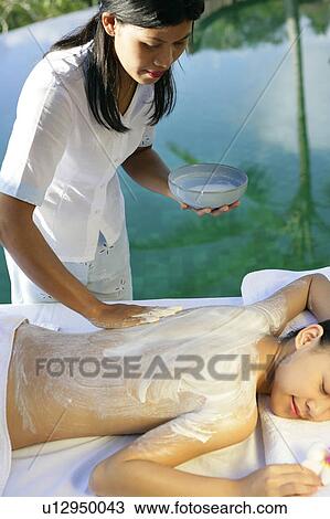 View of a masseuse applying cream on a teenage girl’s back. View Large Photo Image Stock Image - View of a masseuse applying cream on a teenage girl’s back.. Fotosearch