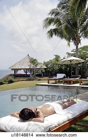 View of a teenage girl sun bathing near a swimming pool. View Large Photo Image Picture - View of a teenage girl sun bathing near a swimming pool.. Fotosearch