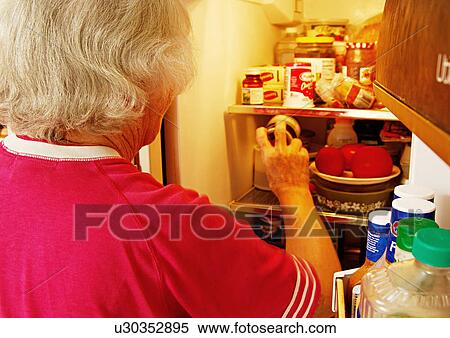Stock Photography - A person having a check in a refrigerator.. Fotosearch