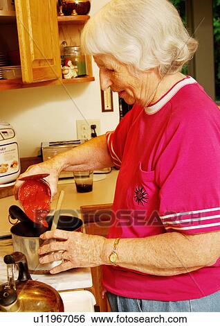 A senior woman preparing food in a kitchen. View Large Photo Image Stock Photograph - A senior woman preparing food in a kitchen.. Fotosearch