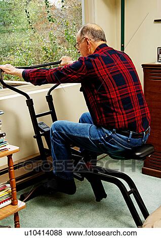Stock Photo - An elderly man working out on an exercycle.. Fotosearch