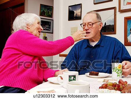 An elderly woman feeding her husband at the breakfast table. View Large Photo Image Stock Image - An elderly woman feeding her husband at the breakfast table.. Fotosearch