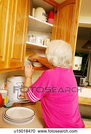 An elderly woman is having a search in a cabinet. View Large Photo Image Stock Image - An elderly woman is having a search in a cabinet.. Fotosearch