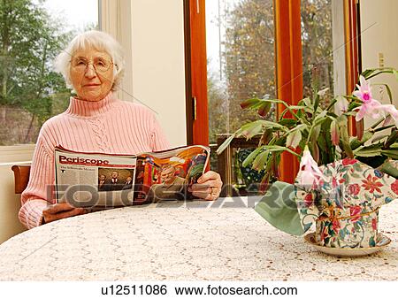 Stock Photograph - An elderly woman reading a magazine.. Fotosearch