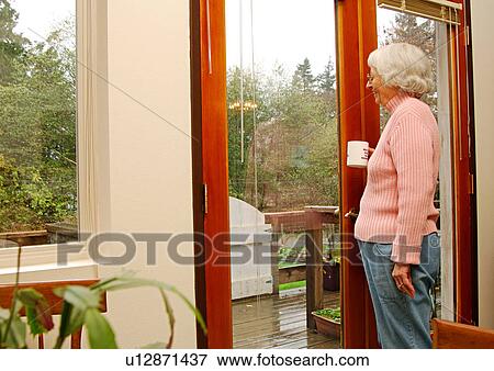 An elderly woman standing at the door admiring the nature. View Large Photo Image Stock Photo - An elderly woman standing at the door admiring the nature.. Fotosearch