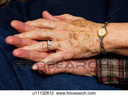 Stock Image - Close-up of a couples clasped hands.. Fotosearch